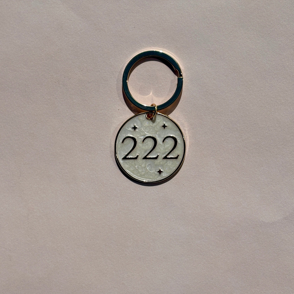 Silver metal keyring with engraved 222 angel number design on pale pink background