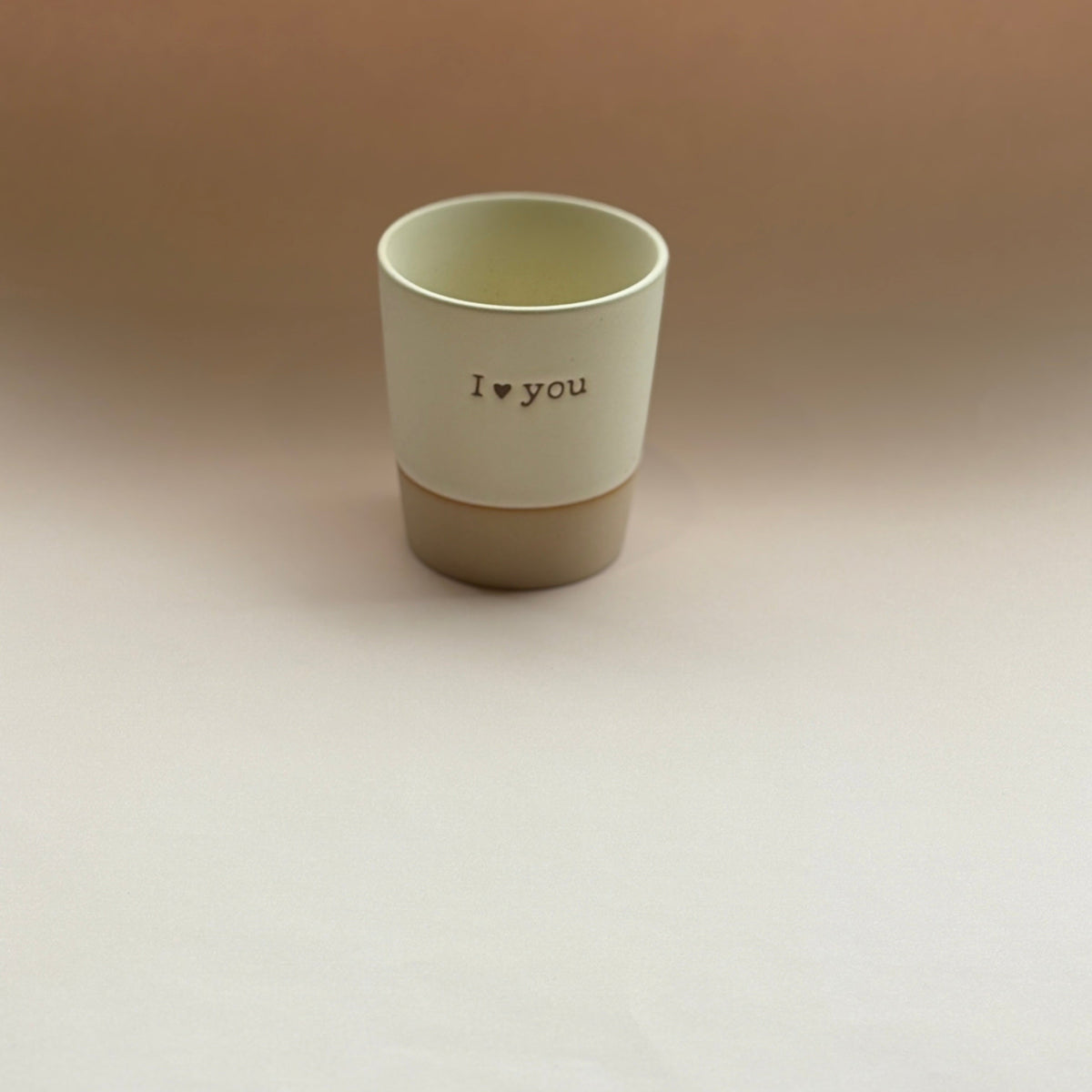 Beige ceramic cup with 'I love you' text on a beige background