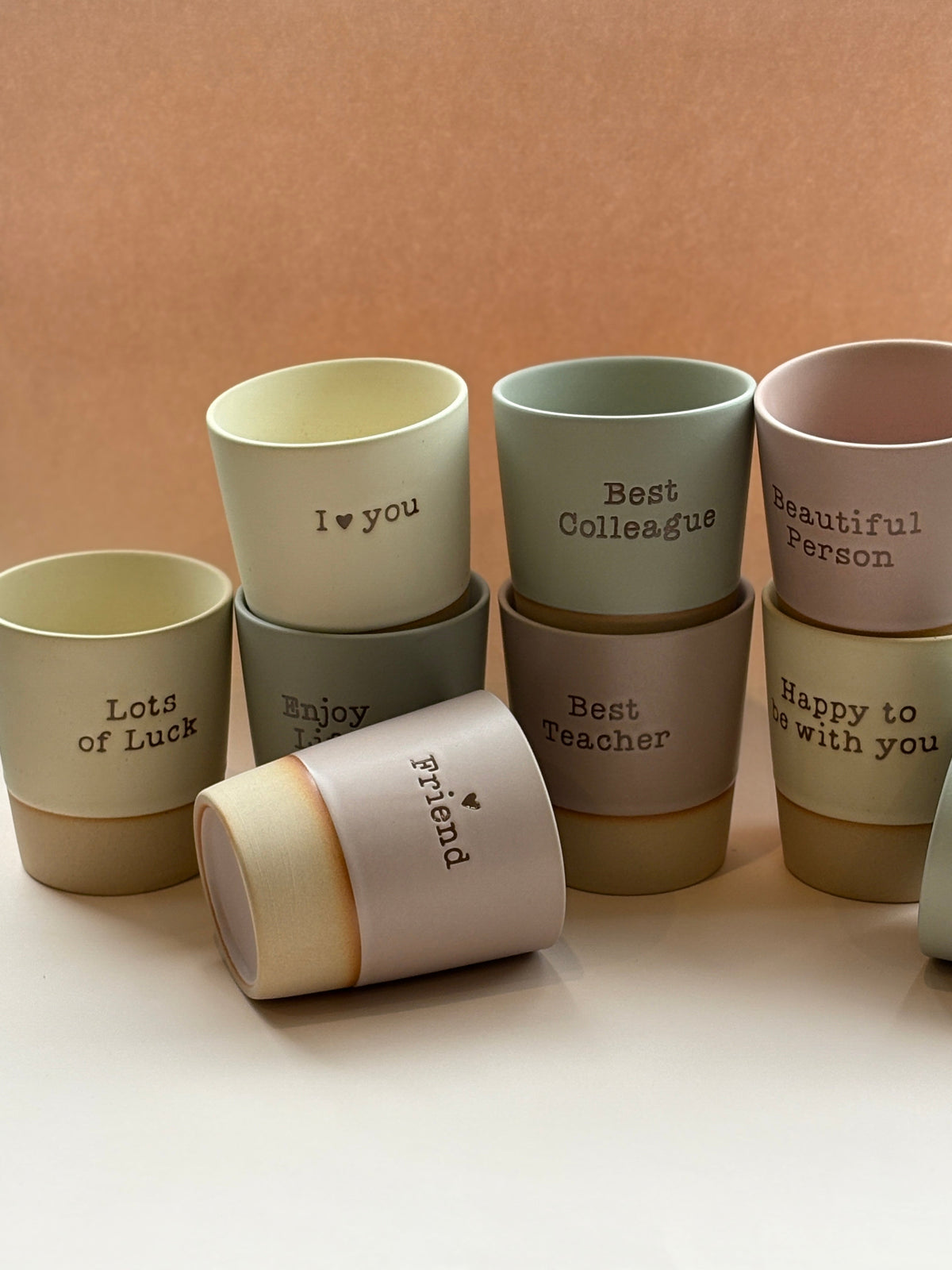 Set of ceramic cups with various messages on a beige background