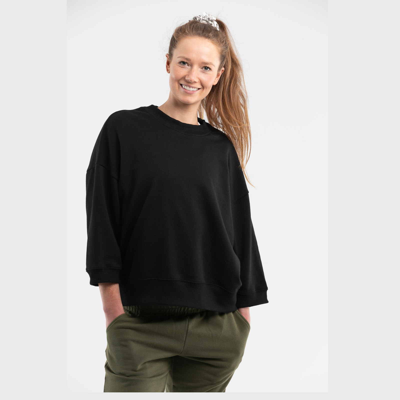 Woman wearing oversized black organic cotton jumper with dropped shoulders on white background