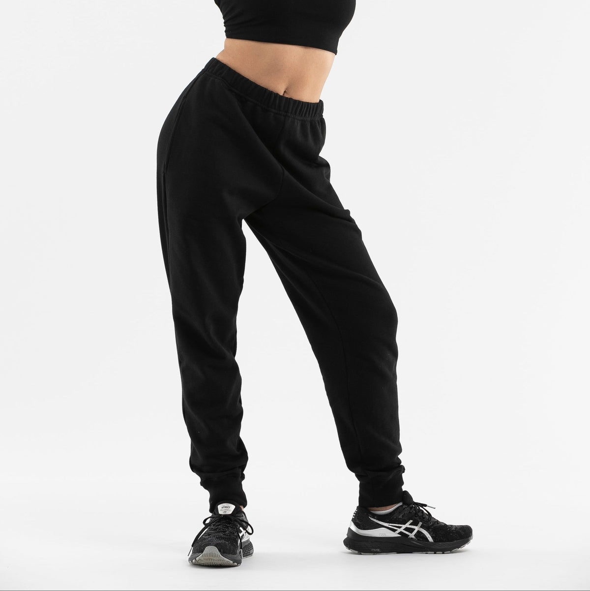 Woman wearing black organic cotton tapered pants with relaxed jumper on white background