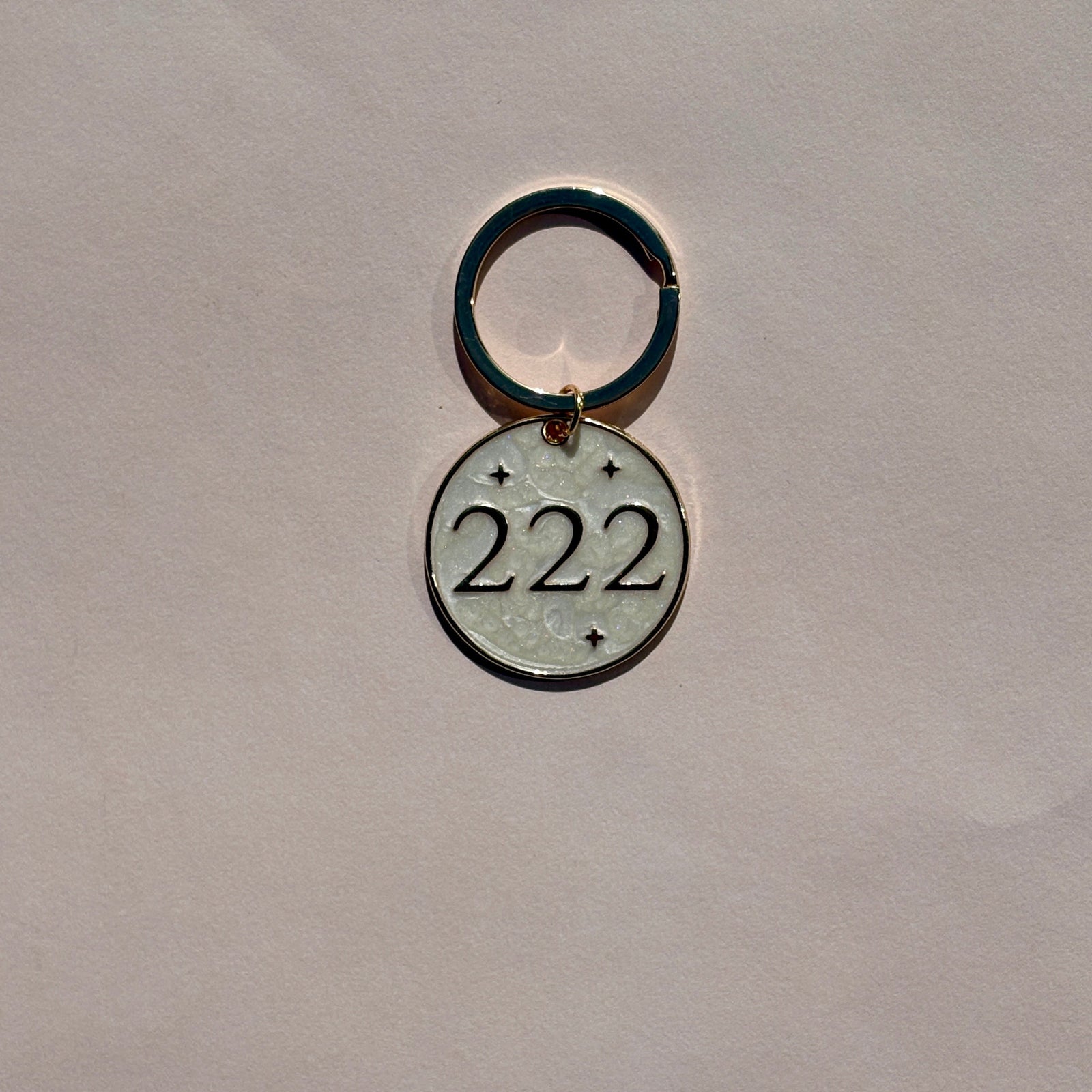 Silver metal keyring with engraved 222 angel number design on pale pink background