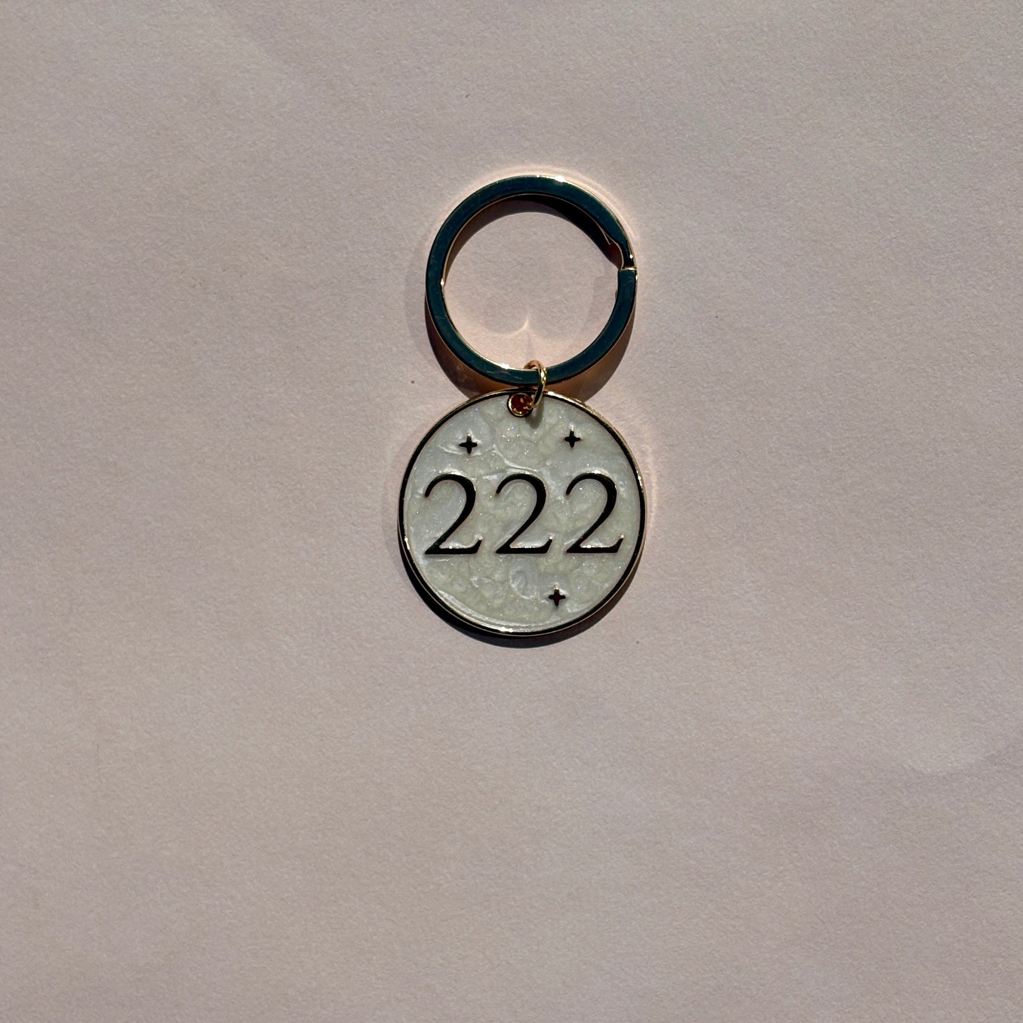 Silver metal keyring with engraved 222 angel number design on pale pink background