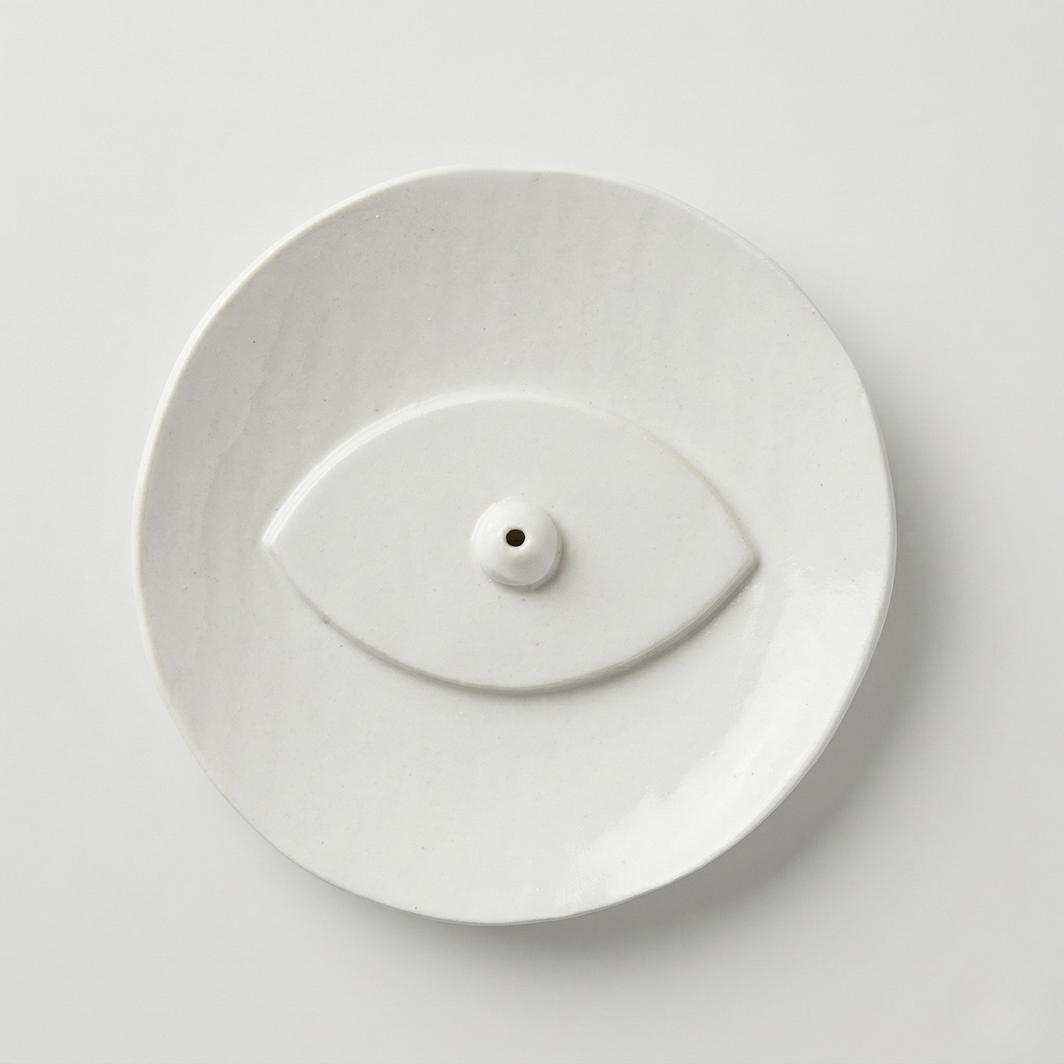White ceramic evil eye incense holder with a minimalist round dish design on a clean white background