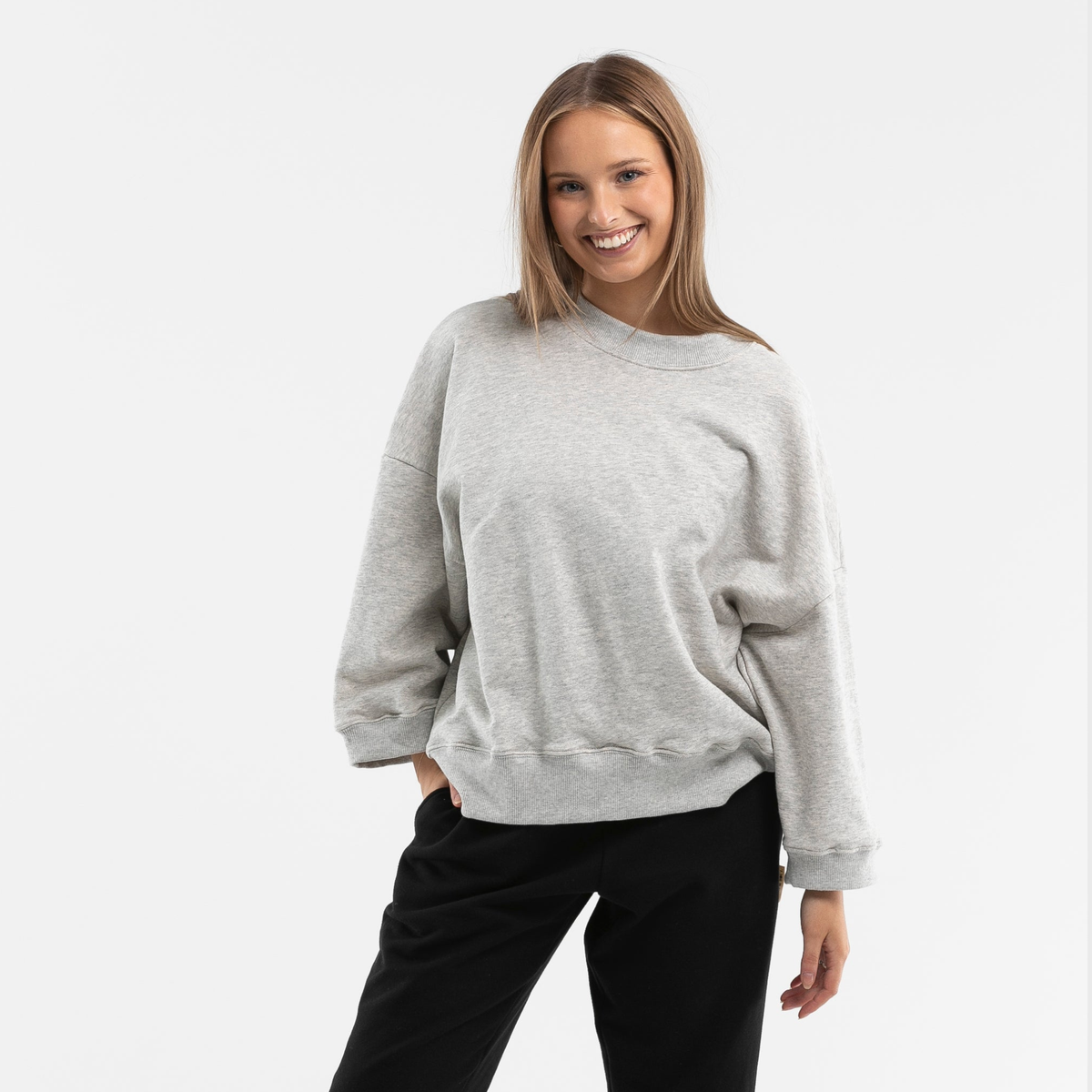 Woman wearing oversized grey organic cotton jumper with dropped shoulders on white background