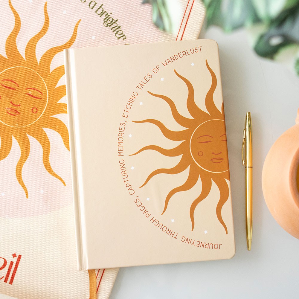 A5 sun design notebook styled with a gold pen and warm-toned decor, perfect for journalling and mindful writing.