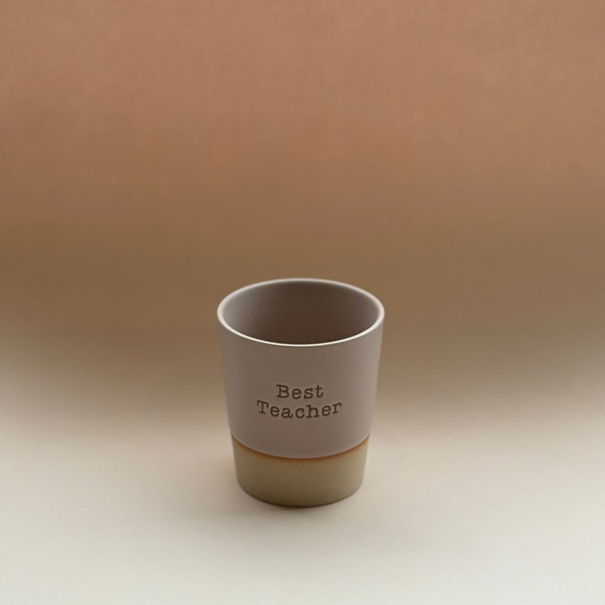 Ceramic cup with &#39;Best Teacher&#39; text on a beige background