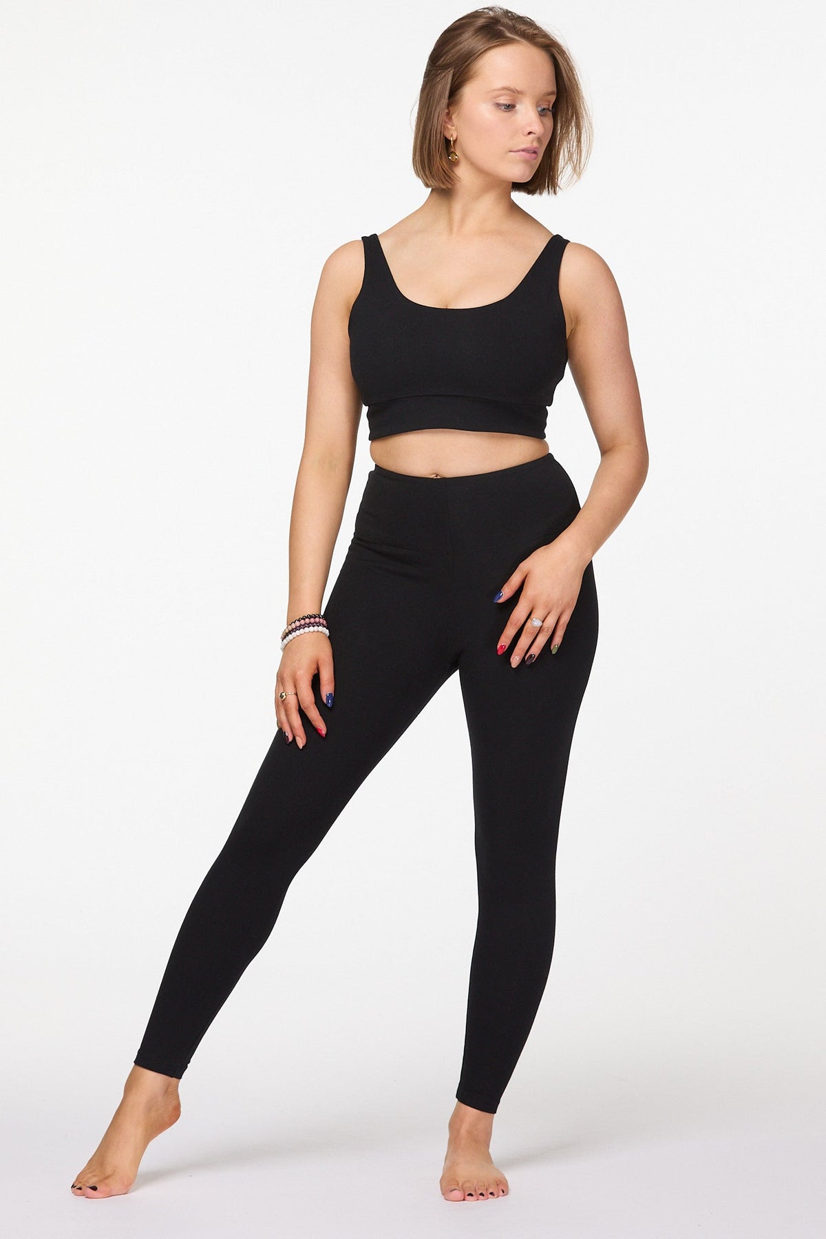 Model wearing black longer leg length high waisted cotton leggings, walking pose 
