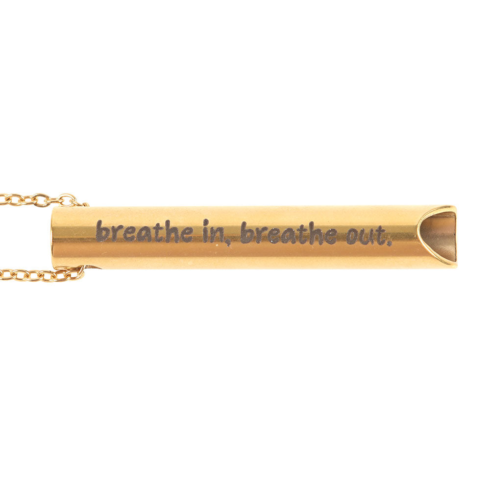 Close-up of gold breathing necklace engraved with “breathe in, breathe out”, designed for mindfulness and calm.
