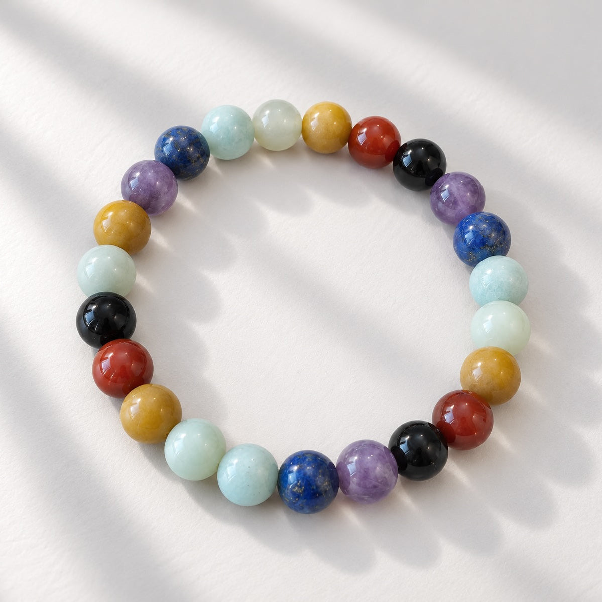 Chakra beaded bracelet with 8 mm round beads in a mix of stones and materials including Carnelian, Amethyst, Garnet, New Jade, Lapis Lazuli, Amazonite and Aventurine.