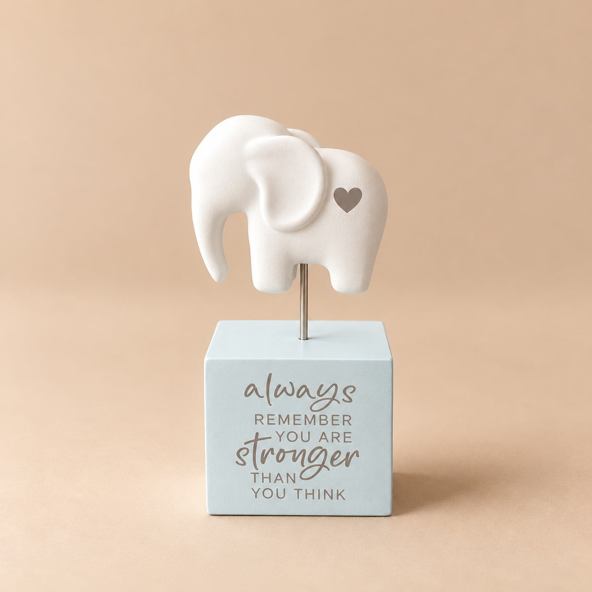 Cream elephant ornament with a small grey heart on its side, raised above a pale mint green square base reading “always remember you are stronger than you think”.