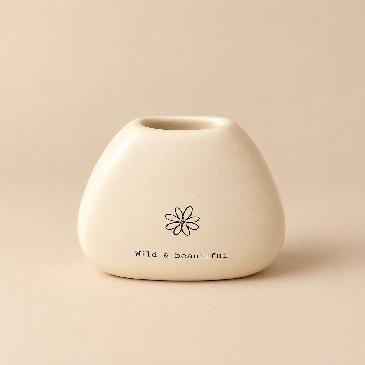 Small rounded cream resin miniature vase with a black flower illustration and “wild & beautiful” lettering.