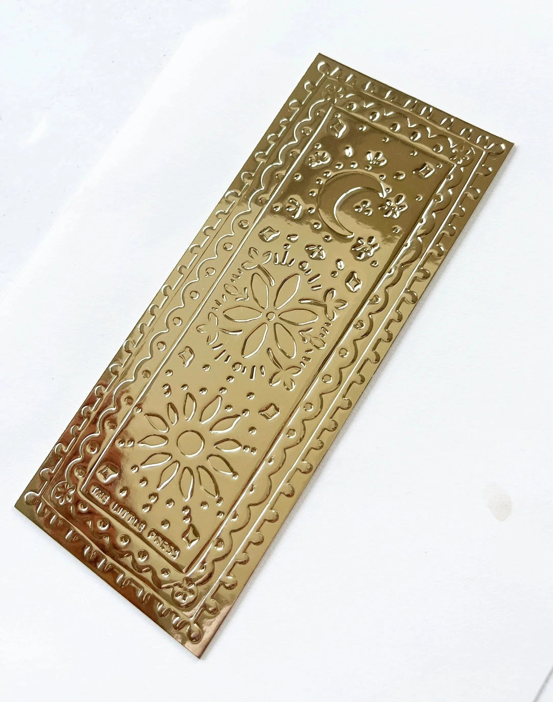 Faux-tin gold bookmark with embossed sun, moon, and flower design