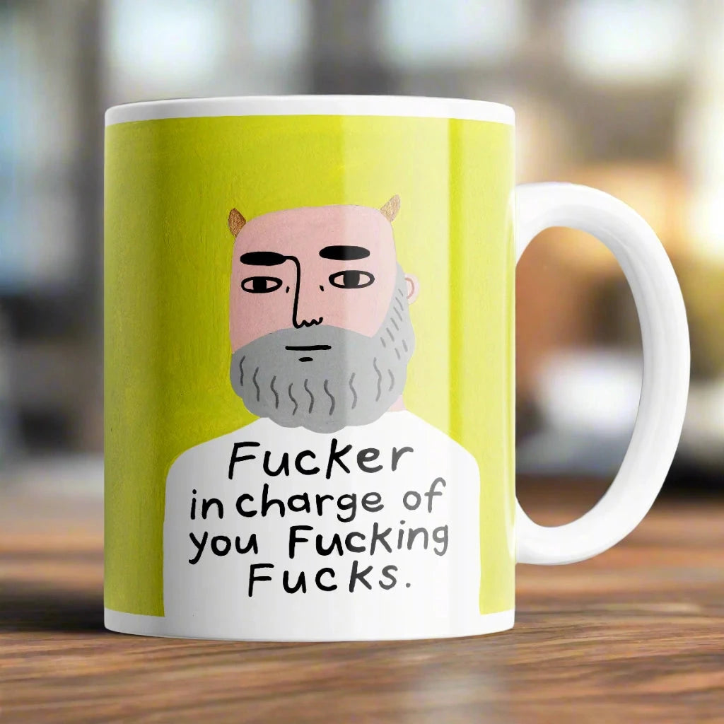 Humorous Fucker in Charge mug sitting on a desk – cheeky 11oz coffee cup gift.