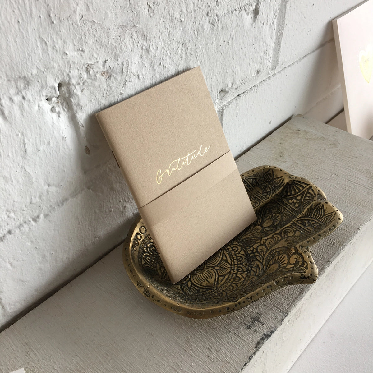 Small gratitude notebook displayed in a decorative tray