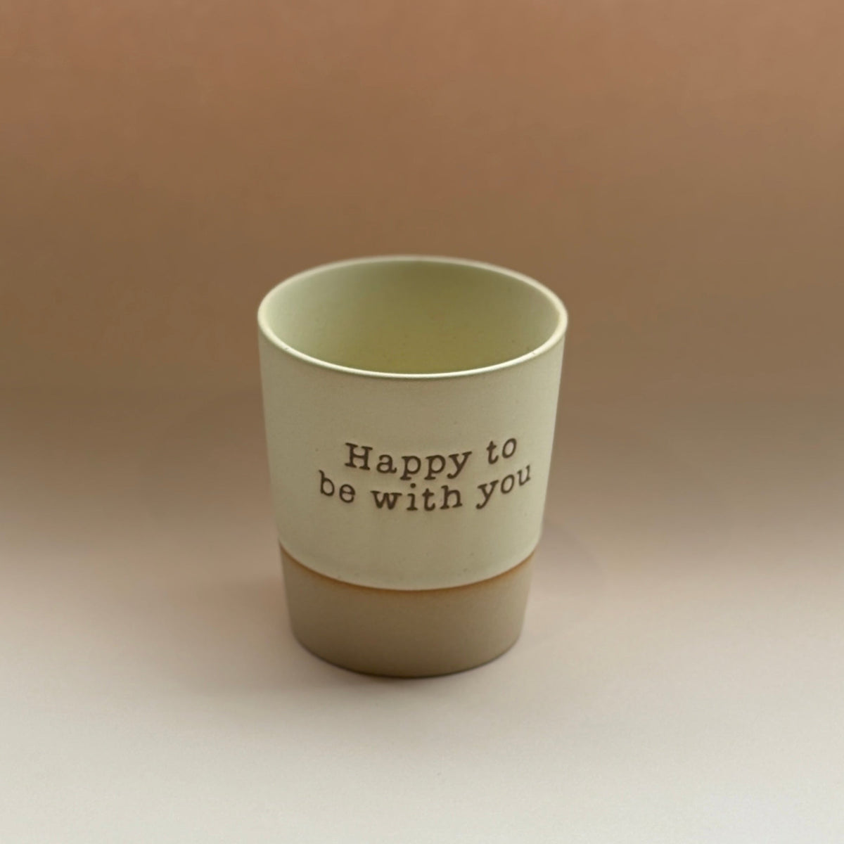 beige ceramic cup with &#39;Happy to be with you&#39; text on a beige background