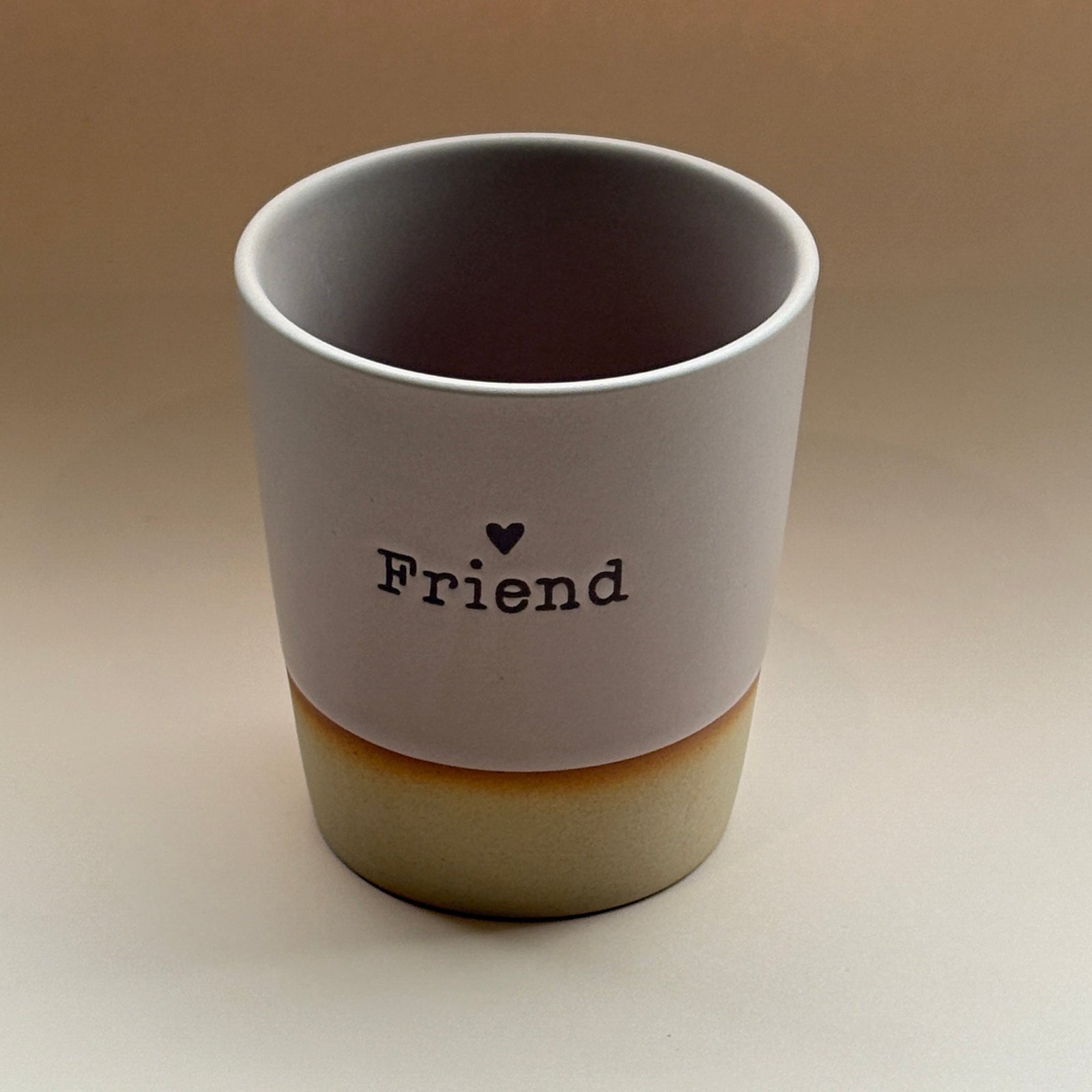 Ceramic cup with 'Friend' and a heart on a beige background