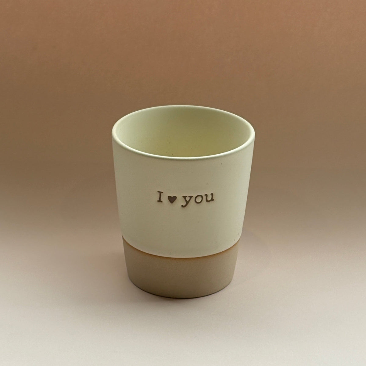 Ceramic cup with &#39;I love you&#39; text on a beige background