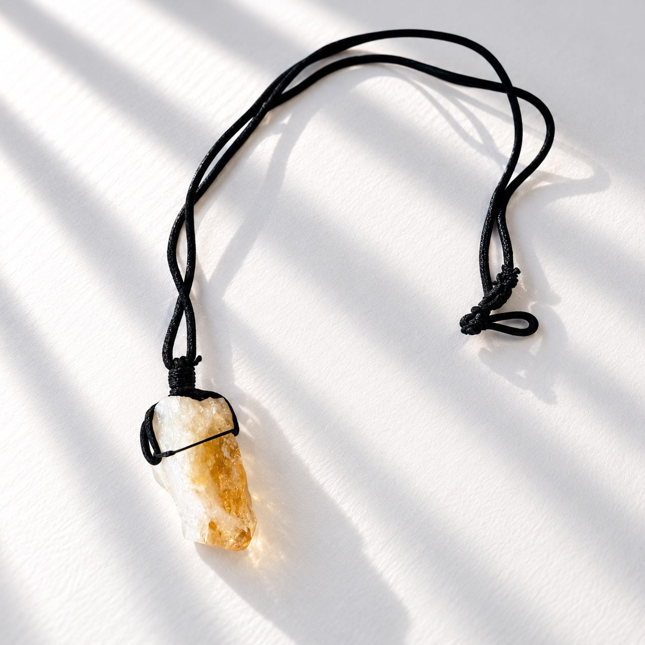 Natural raw citrine crystal pendant tied onto a simple black cord necklace.