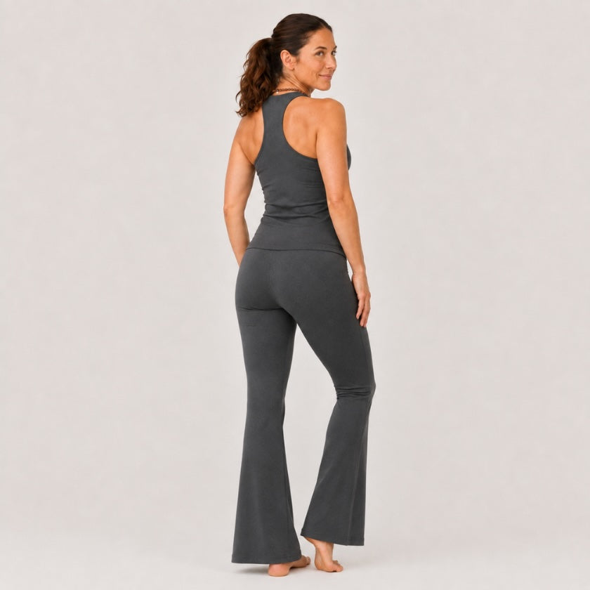 Woman wearing dark grey organic cotton long leg flare yoga pants with high waisted fit against neutral studio background.