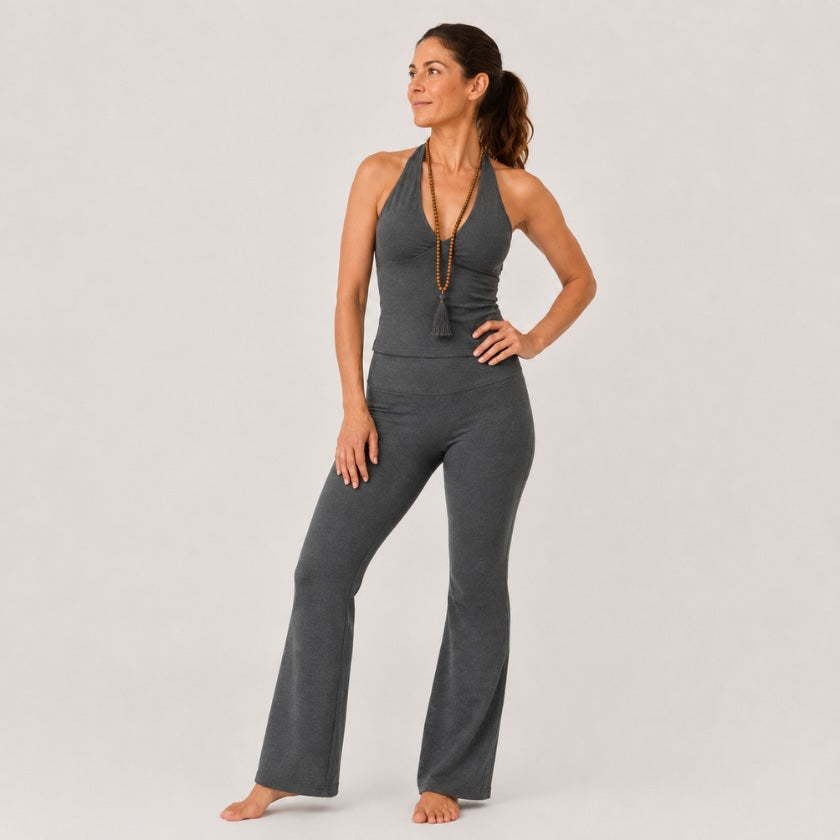 Woman wearing dark grey organic cotton long leg flare yoga pants with high waisted fit against neutral studio background