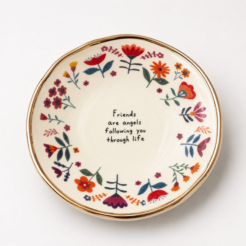 Ceramic floral trinket bowl with colourful hand painted style flowers, gold rim detail and “Friends are angels following you through life” quote in the centre.