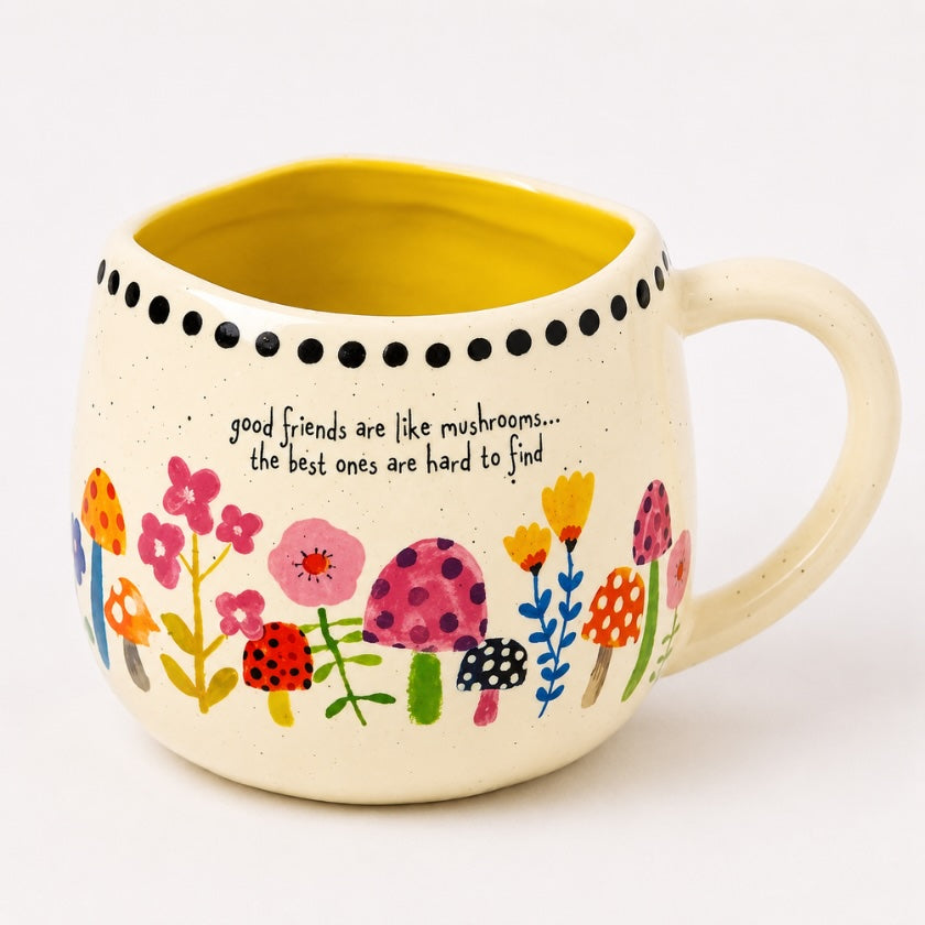 Speckled ceramic mug with colourful mushroom and floral illustrations, yellow interior and “Good friends are like mushrooms… the best ones are hard to find” quote.