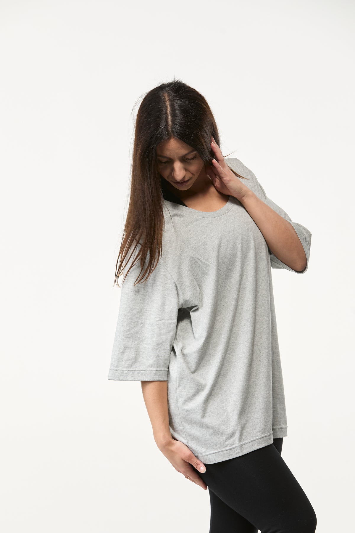 Woman styling a grey oversized tee with black leggings, loose comfortable fit for studio and lounge wear
