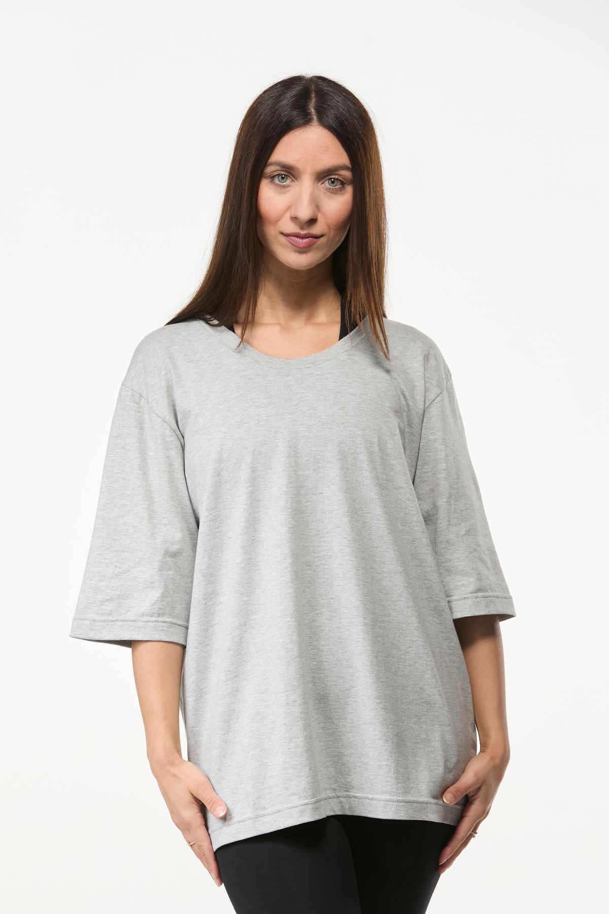 Woman wearing a grey oversized tee with black leggings, relaxed fit top for yoga and everyday wear