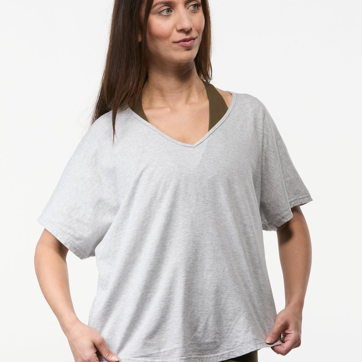 Woman wearing a grey V-neck relaxed yoga top with olive leggings, soft everyday fit