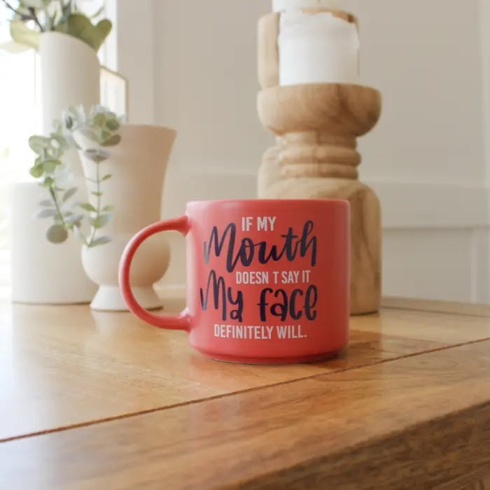 Coral red 390ml ceramic mug with If my mouth doesn’t say it my face definitely will cheeky quote styled on table.