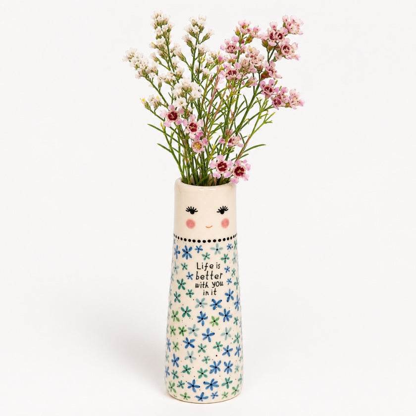 Ceramic floral vase with hand painted blue and green flower pattern, smiling face detail and “Life is better with you in it” quote, styled with pink and white flowers.