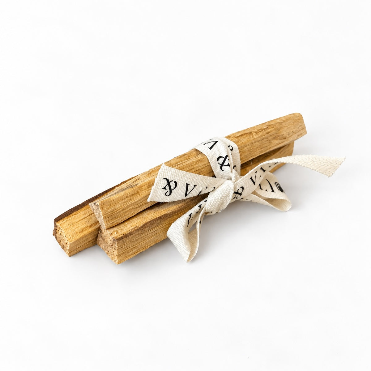 Bundle of Palo Santo wooden sticks tied with printed cream ribbon on a white background.