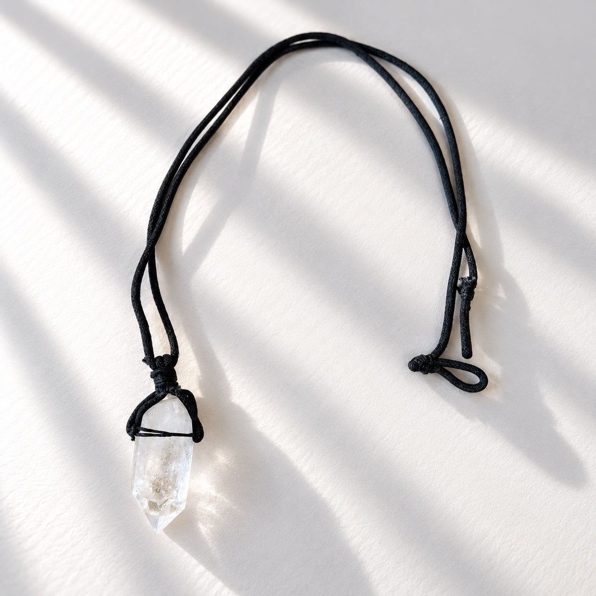 Raw clear quartz crystal necklace with natural crystal pendant on black cord.