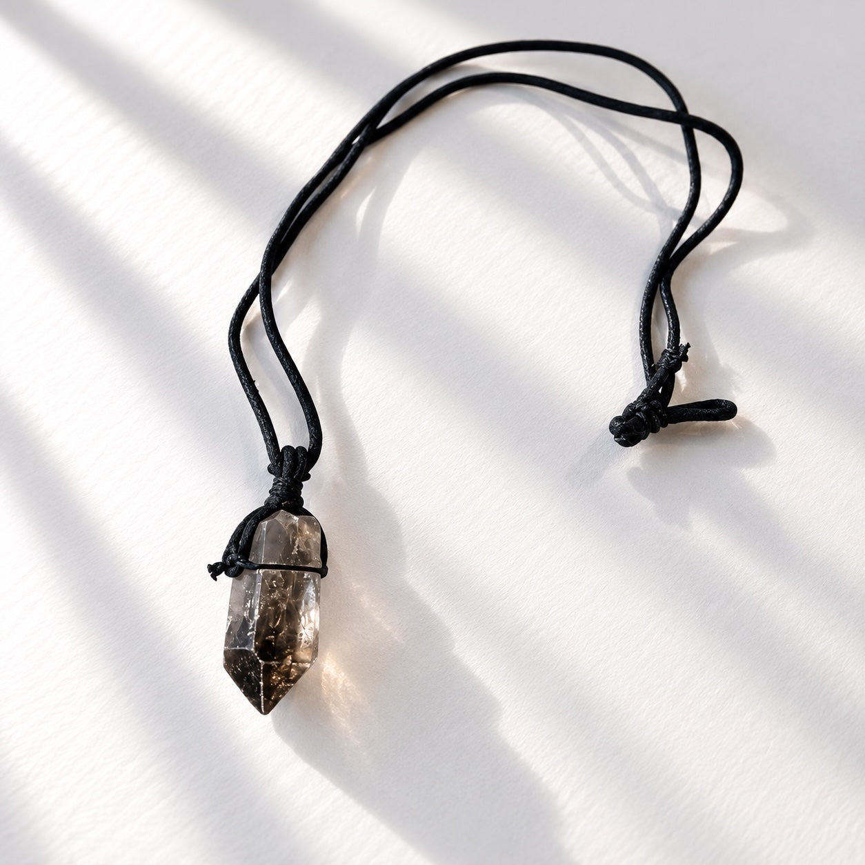 Natural raw smokey quartz crystal point pendant on black cord necklace.