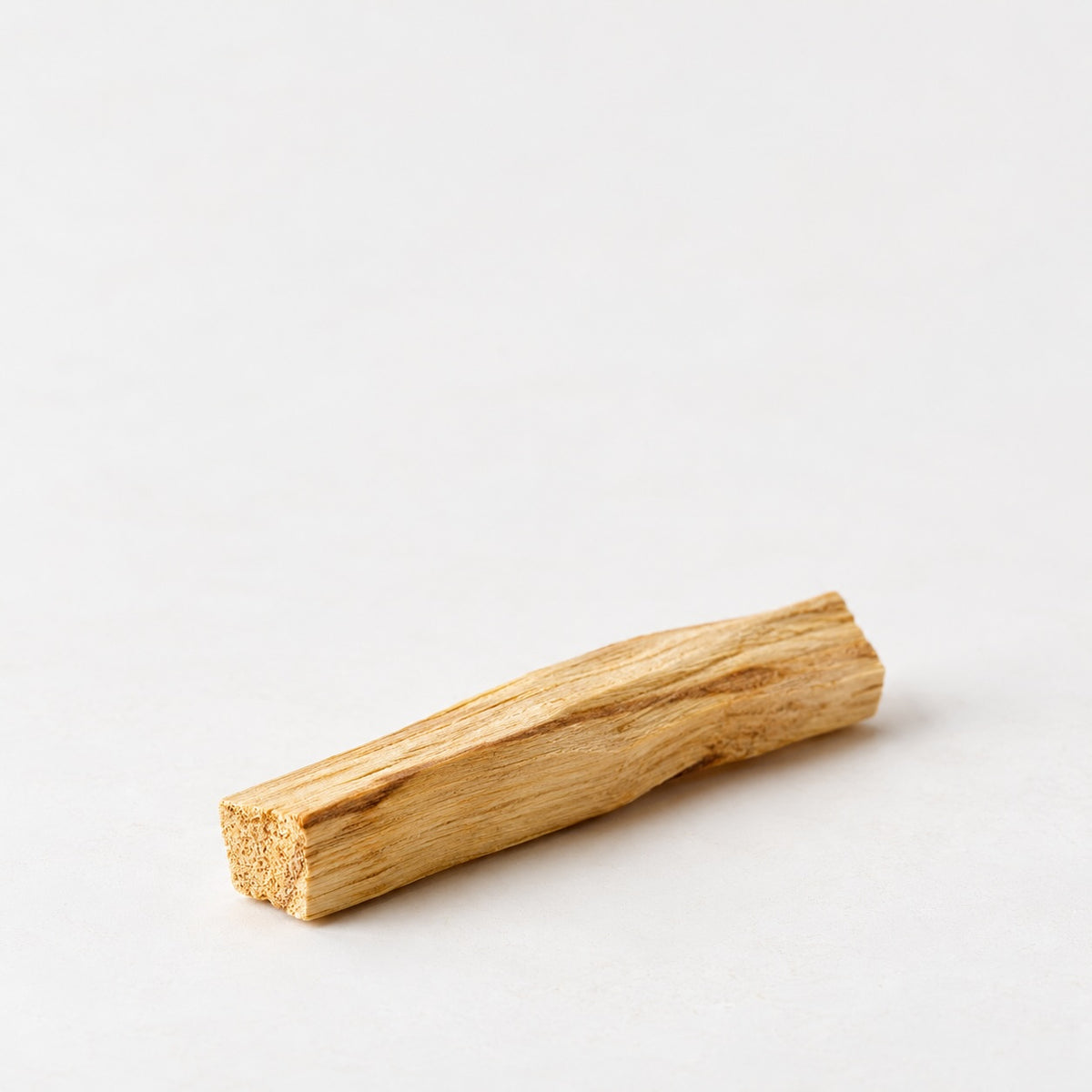 Palo Santo wood stick with natural grain on a neutral background.