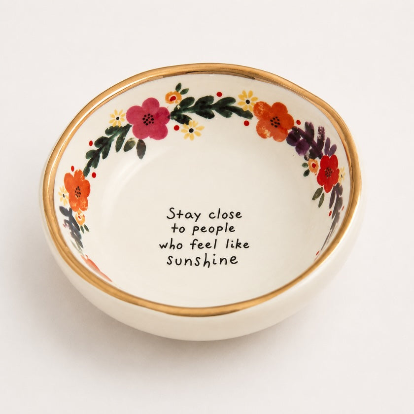White ceramic bowl with hand painted floral border, gold rim detail and “Stay close to people who feel like sunshine” quote in the centre.