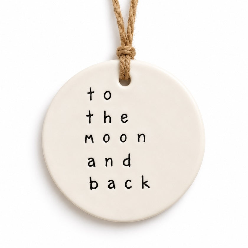 Cream round To The Moon And Back ceramic tag with hanging cord.