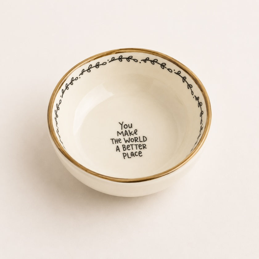White ceramic bowl with gold rim, delicate black border detail and “You make the world a better place” quote in the centre.