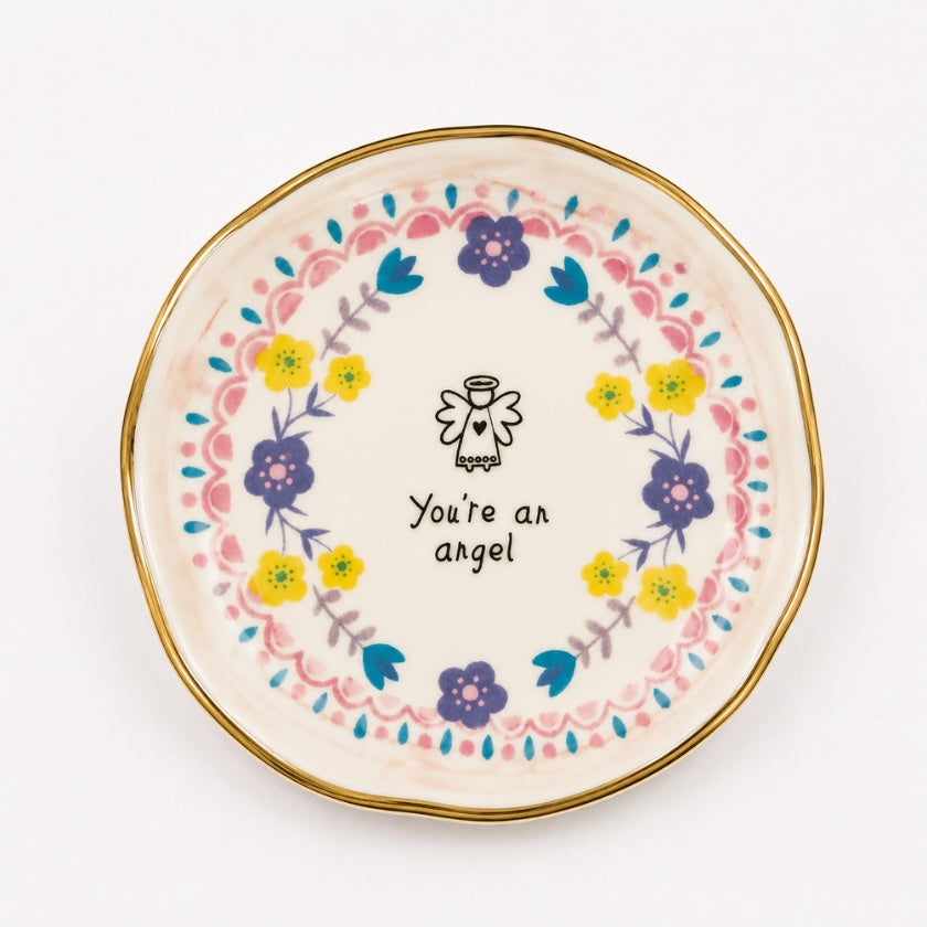 White ceramic trinket bowl with pastel floral wreath design, gold rim detail and “You’re an angel” quote with angel illustration in the centre.