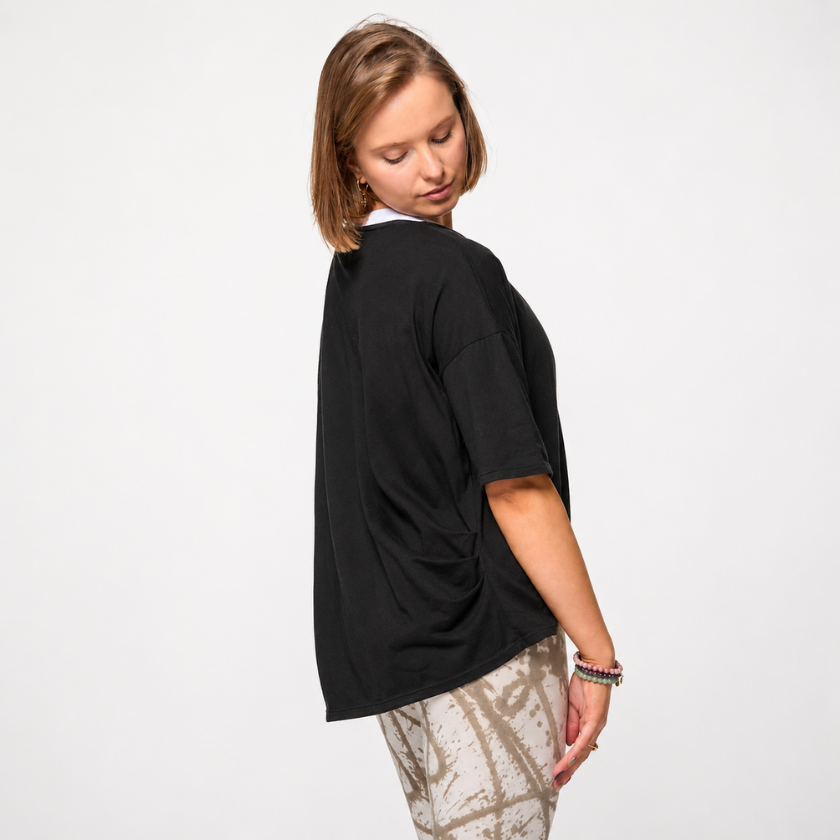 Three-quarter back view of Luna &amp; Soul Zen organic cotton yoga top in black — hi-low hem detail