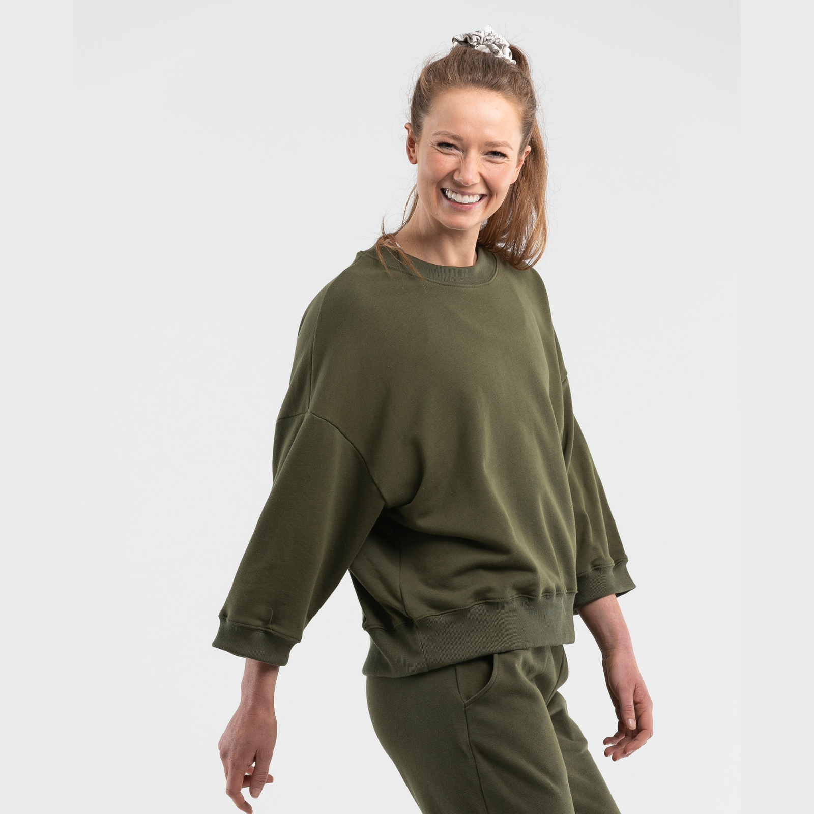 Woman wearing khaki organic cotton oversized jumper with relaxed fit on white background