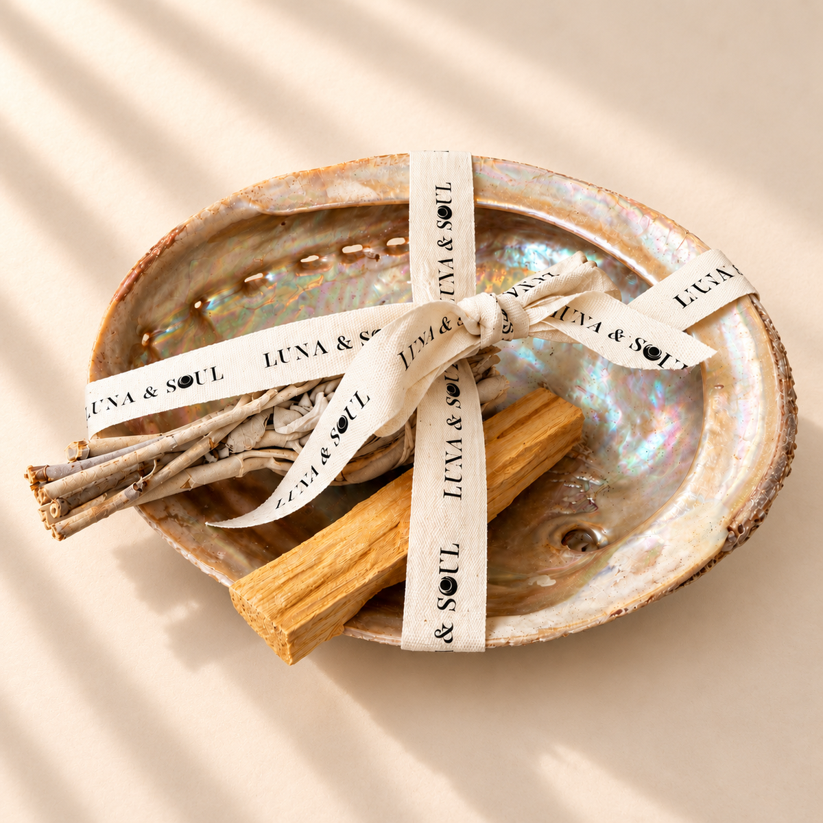 Luna &amp; Soul smudging kit featuring a natural iridescent abalone shell, white sage bundle and Palo Santo wood stick, beautifully presented with branded cotton ribbon.