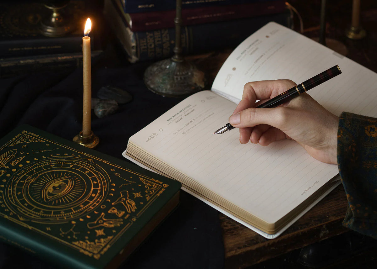 Stack of Magic of I 2026 planners and almanacs in assorted colours styled on vintage desk