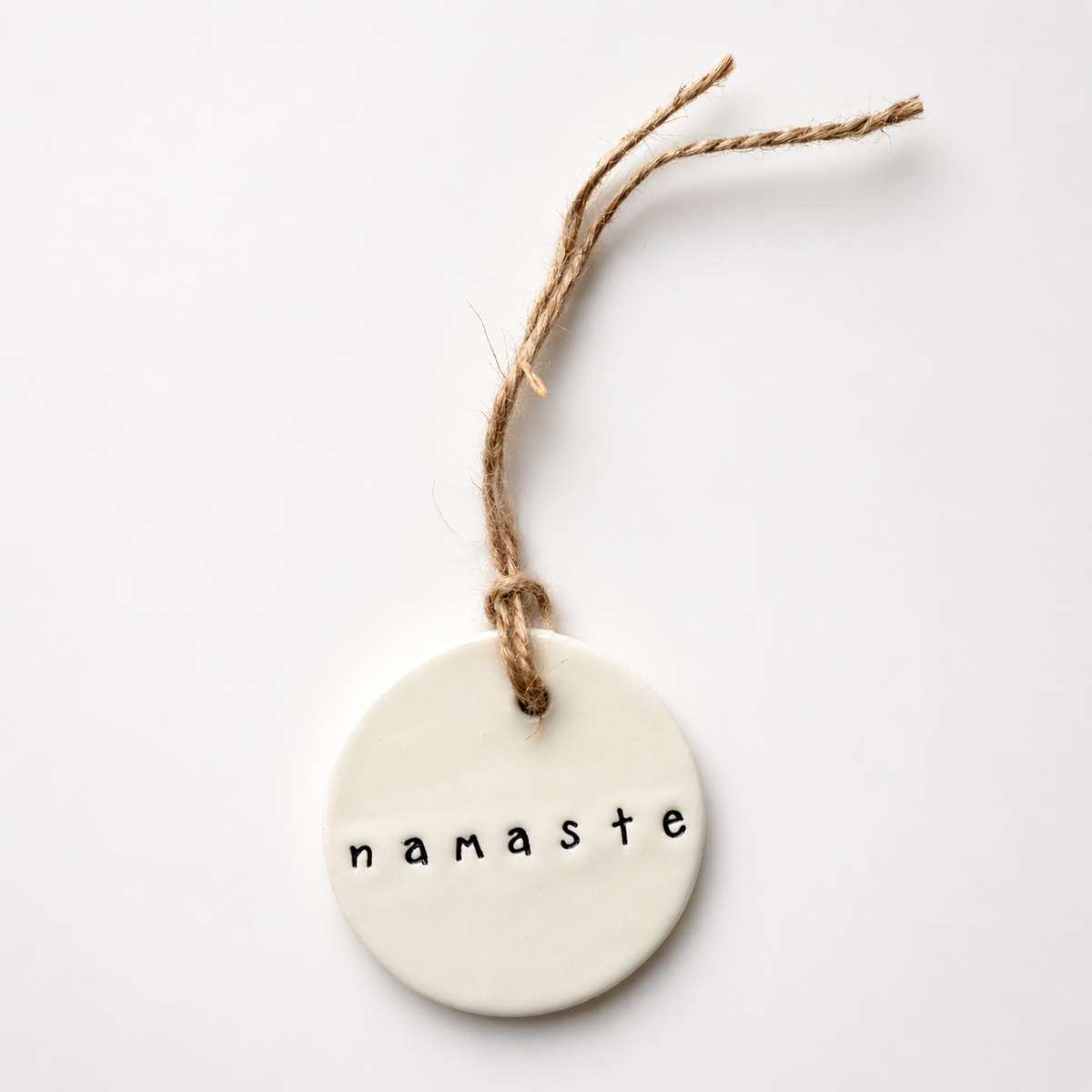 Handmade Namaste ceramic tag made in Australia with glossy white earthenware clay and jute twine
