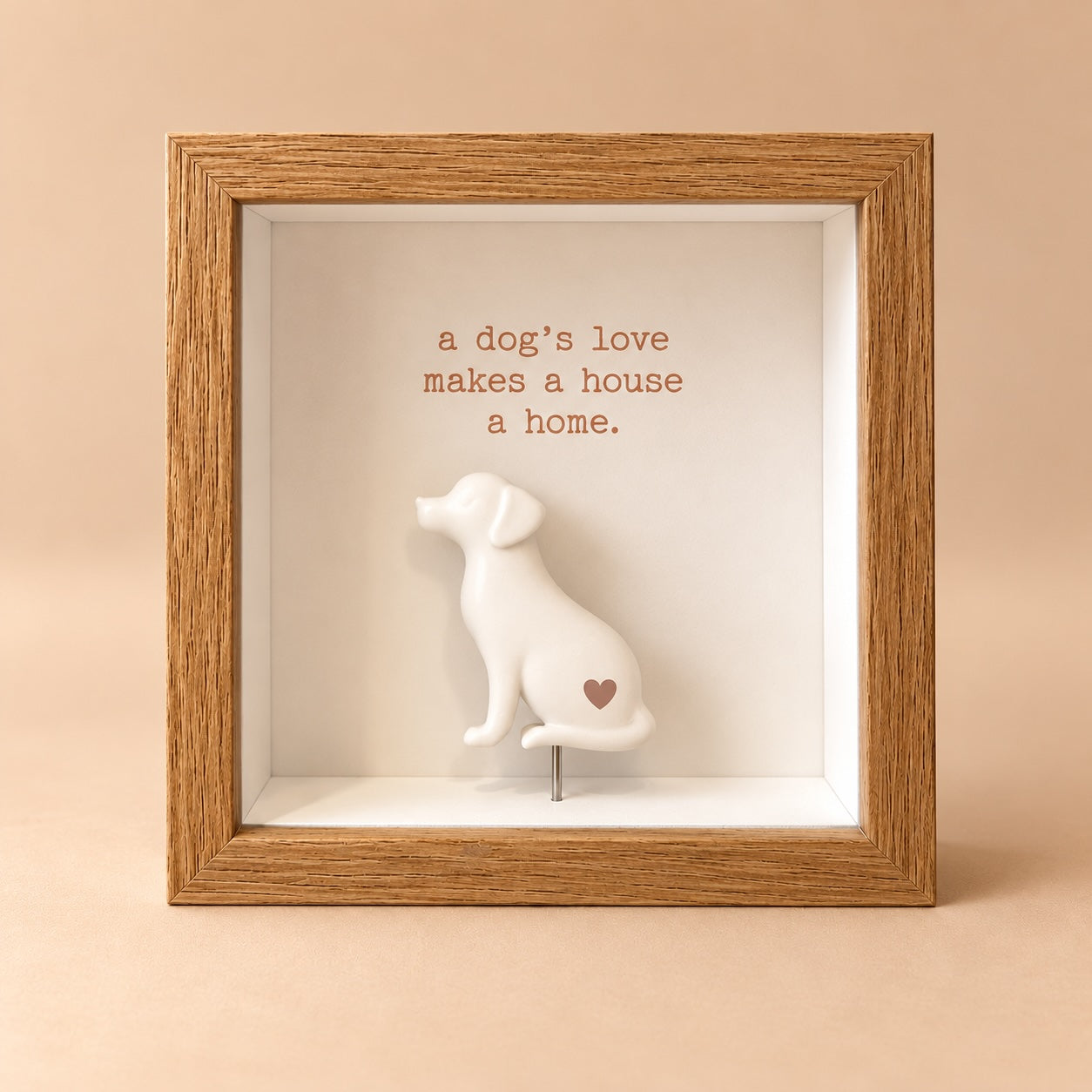 Oak finish square 3D shadowbox frame with “a dog’s love makes a house a home” quote and raised white sitting dog figurine with a small heart.