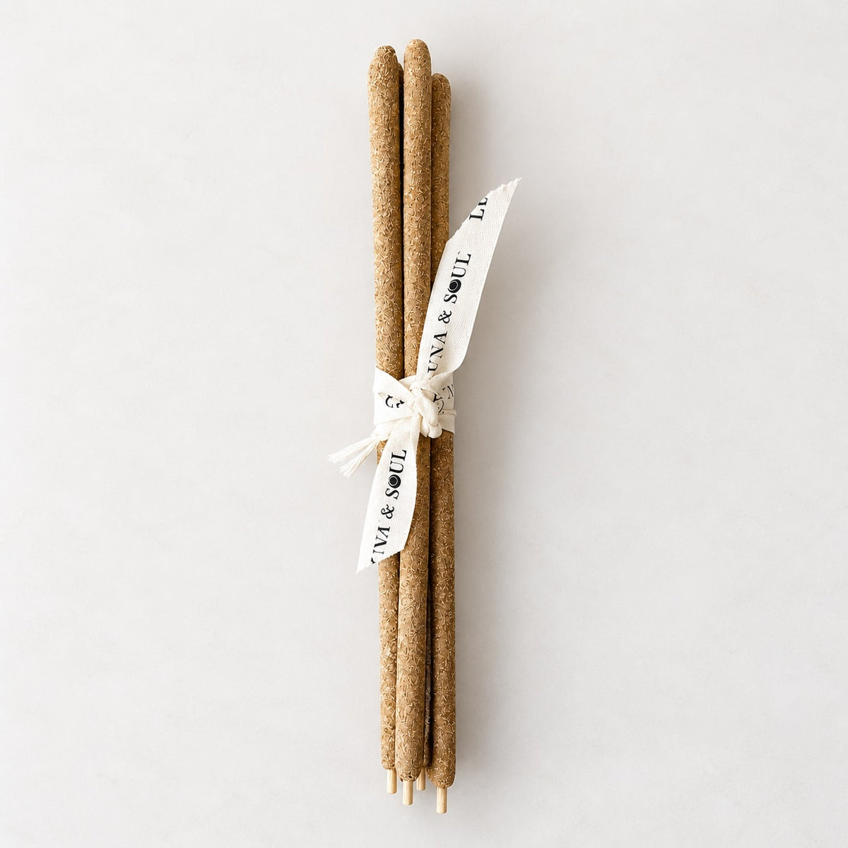 Four Palo Santo sticks bundled with a cream printed ribbon, shown on a neutral background.