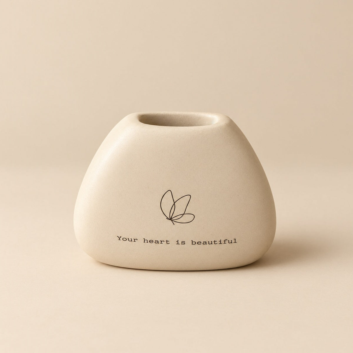 Rounded sand coloured mini resin vase with a black butterfly line illustration and “Your heart is beautiful” lettering.