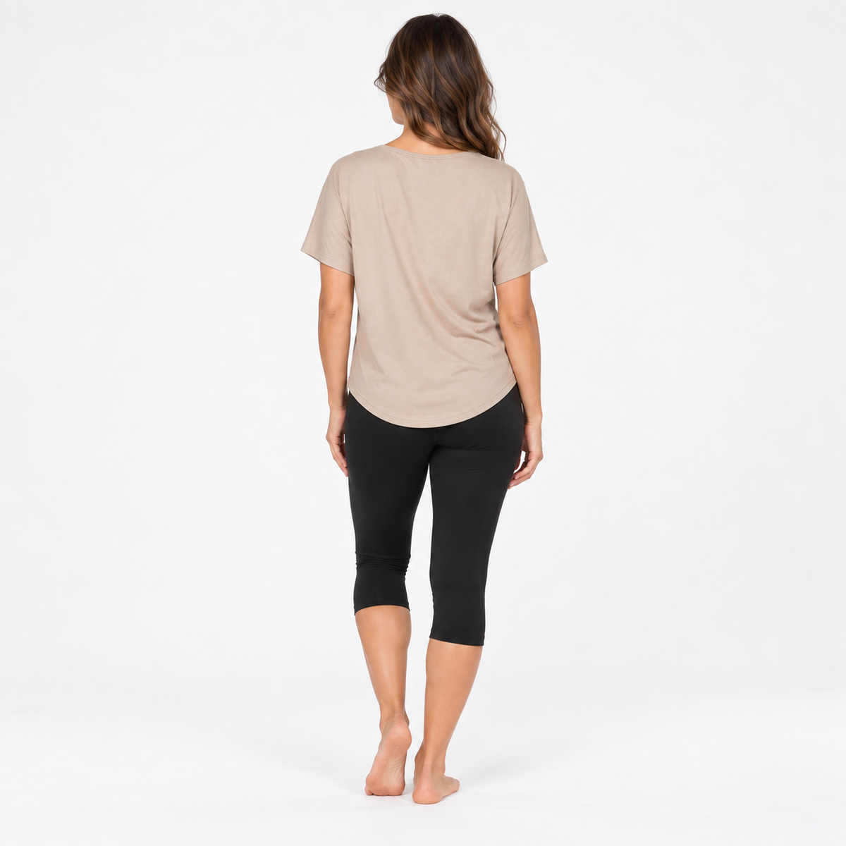 Back view of the V Neck T-Shirt in sand organic cotton, a relaxed fit yoga tee with a curved hem, styled with the Asana Capri Leggings in black by Luna &amp; Soul