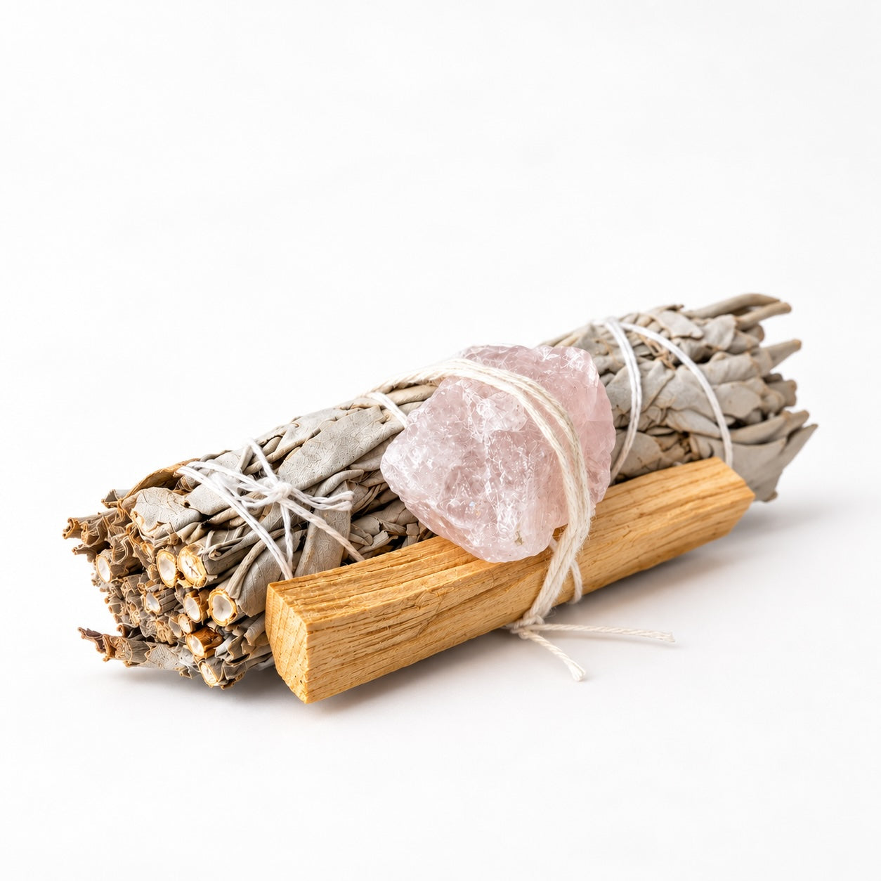 White Sage smudge stick tied with Palo Santo wood and Rose Quartz crystal in a ritual kit.